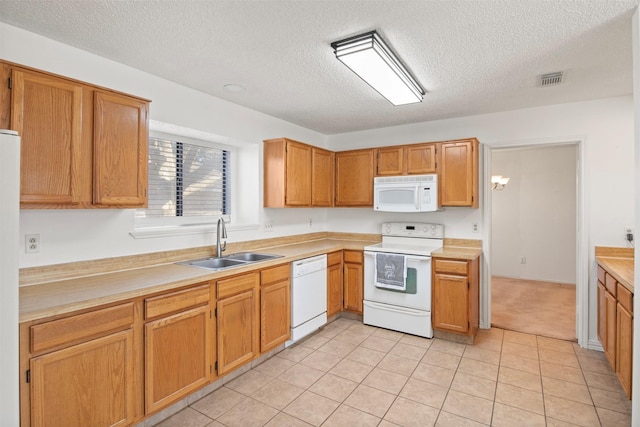 kitchen featuring white appliances, sink, a textured ceiling, and light tile patterned floors