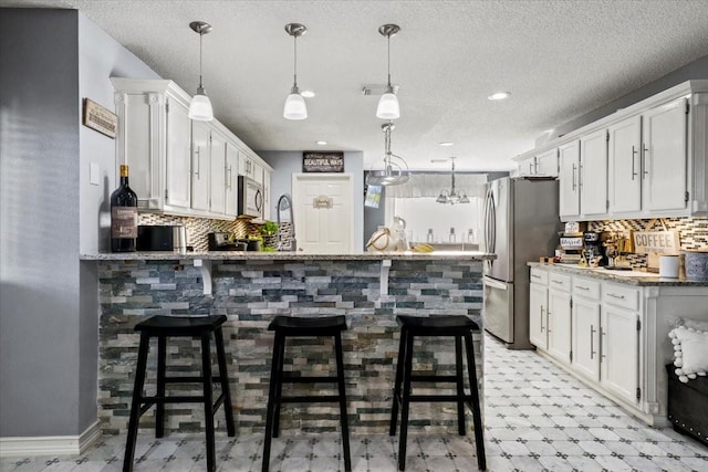 kitchen featuring white cabinetry, stainless steel appliances, a breakfast bar, and kitchen peninsula