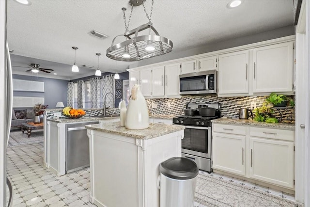 kitchen with appliances with stainless steel finishes, a center island, hanging light fixtures, and white cabinets