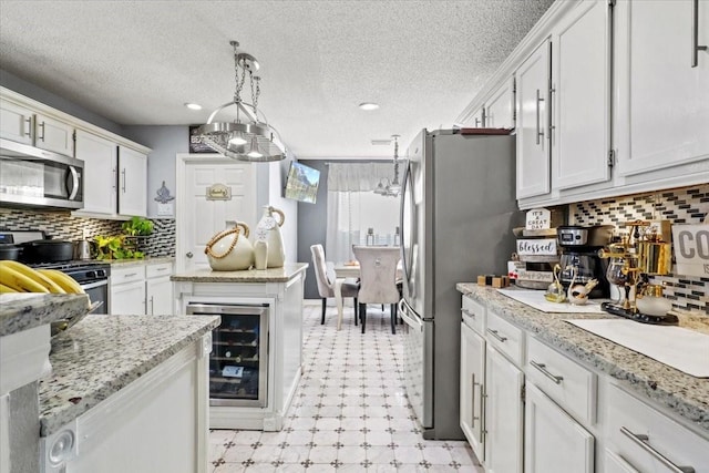 kitchen featuring white cabinetry, stainless steel appliances, beverage cooler, and decorative light fixtures