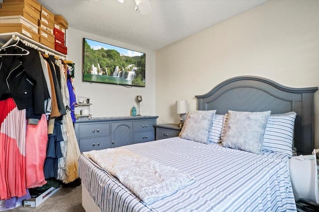 bedroom with ceiling fan, carpet floors, and a textured ceiling