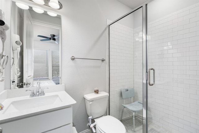 bathroom featuring a shower with door, vanity, ceiling fan, and toilet