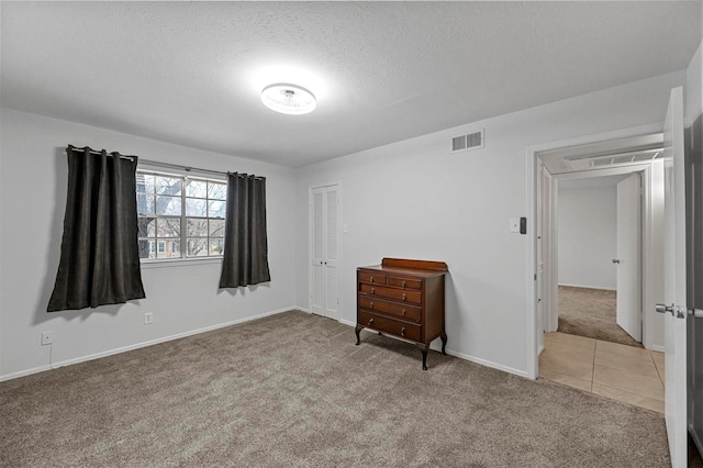 unfurnished bedroom featuring light colored carpet, a closet, and a textured ceiling