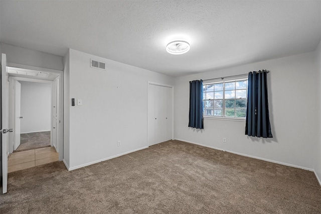 unfurnished bedroom with carpet flooring, a closet, and a textured ceiling