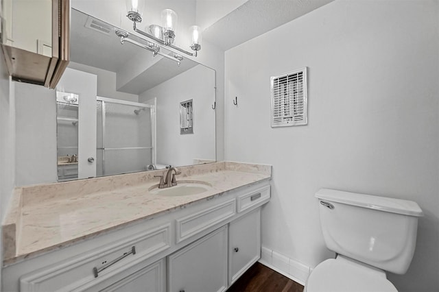 bathroom with hardwood / wood-style flooring, vanity, a shower with door, and toilet