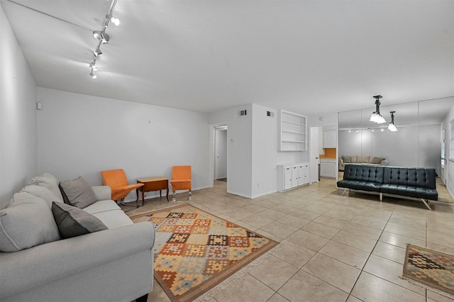 living room with built in features, light tile patterned floors, and track lighting