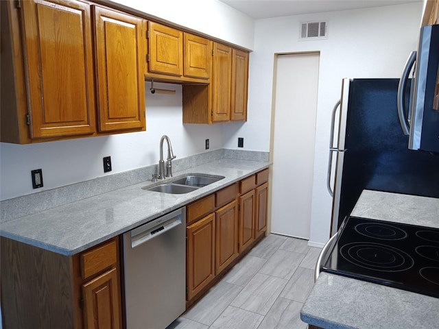 330 W Harwood Rd Unit C, Hurst, TX 76054 - kitchen with appliances with stainless steel finishes, a sink, brown cabinetry, and light countertops
