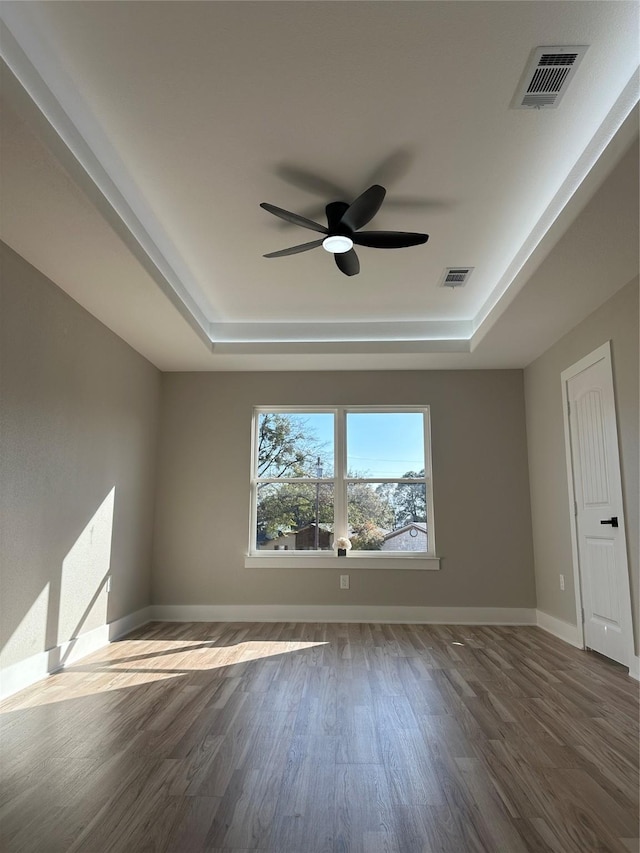 unfurnished room featuring ceiling fan, dark hardwood / wood-style floors, and a raised ceiling