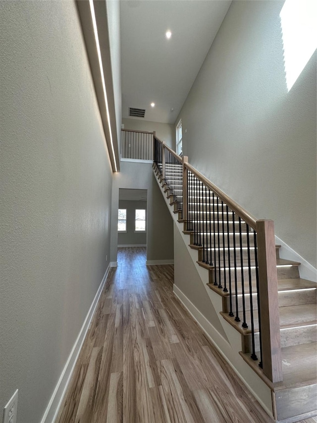 stairs with hardwood / wood-style flooring and a high ceiling