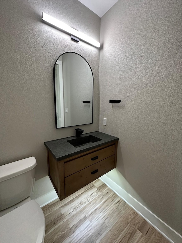 bathroom with vanity, toilet, and wood-type flooring