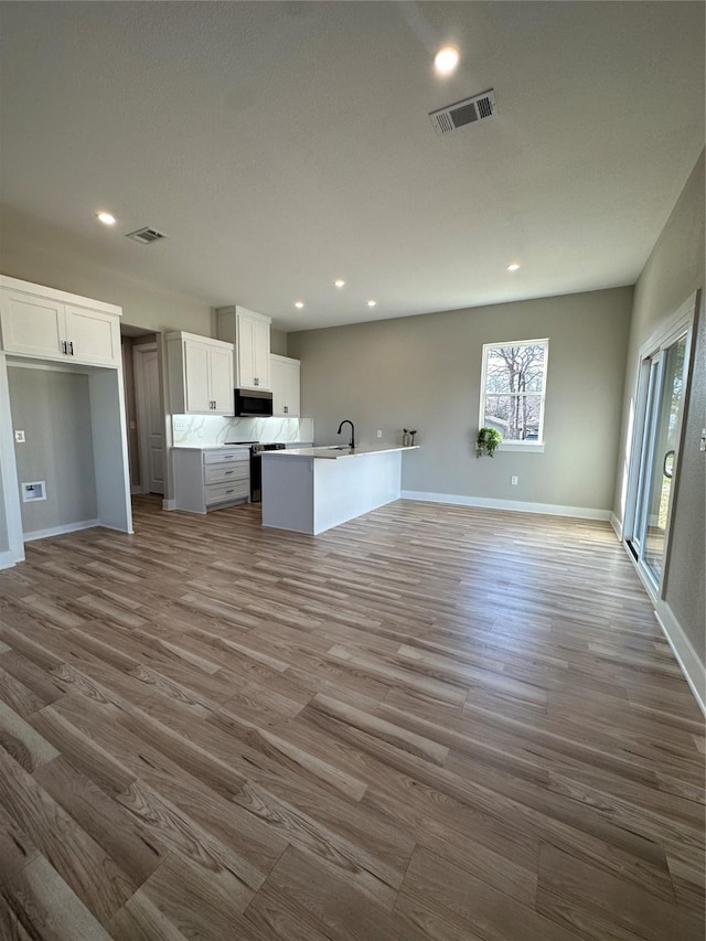 kitchen featuring white cabinetry, sink, a kitchen island with sink, and light hardwood / wood-style flooring