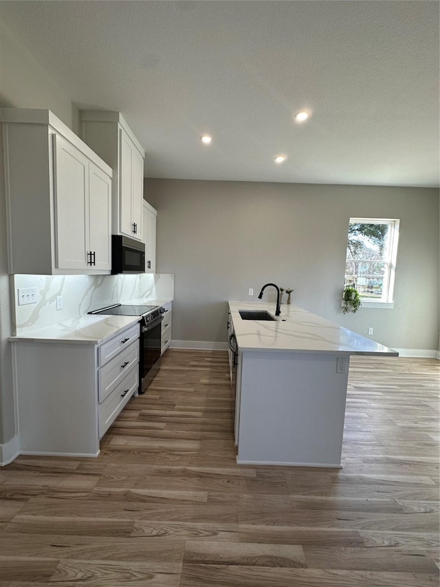 kitchen featuring sink, tasteful backsplash, wood-type flooring, white cabinets, and black range with electric cooktop