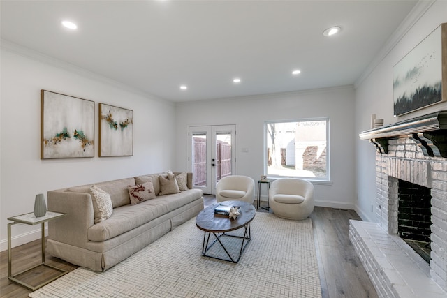 living room featuring french doors, crown molding, a brick fireplace, and light wood-type flooring