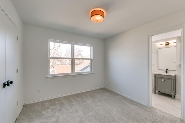 unfurnished bedroom featuring ensuite bathroom and light carpet