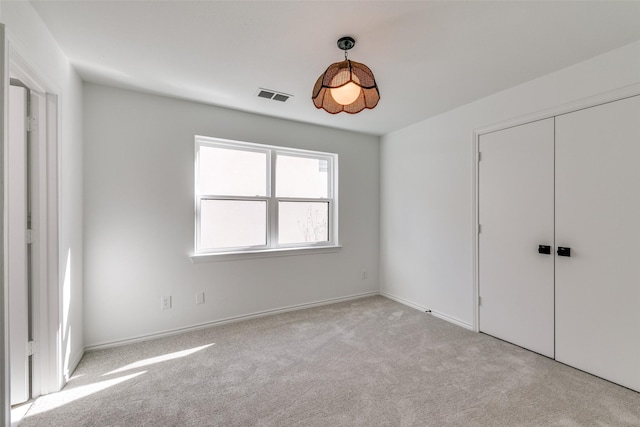 unfurnished bedroom with light carpet and a closet