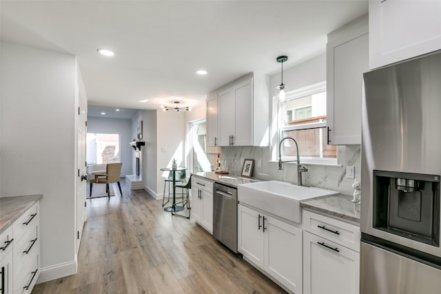 kitchen featuring appliances with stainless steel finishes, decorative light fixtures, tasteful backsplash, white cabinetry, and sink