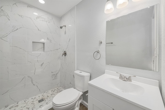 bathroom featuring vanity, toilet, and a tile shower