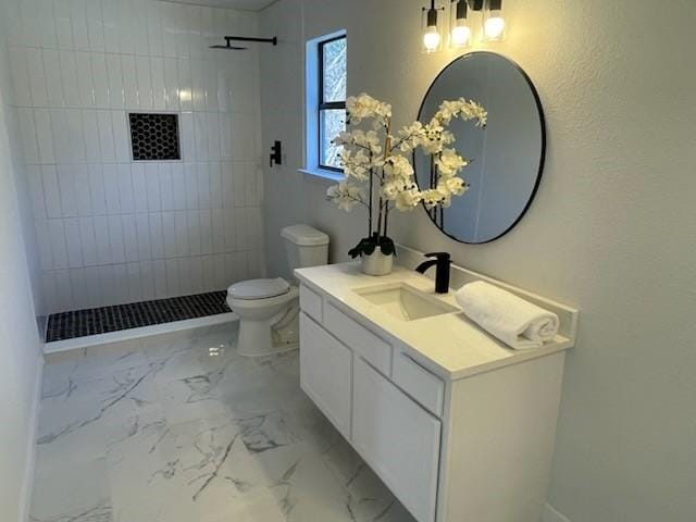 bathroom featuring vanity, toilet, and tiled shower