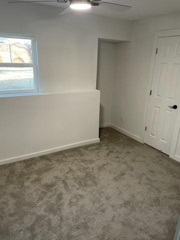 spare room with ceiling fan and dark colored carpet