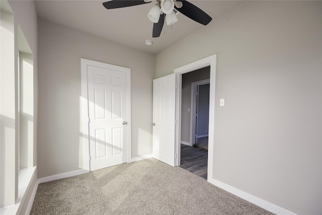 unfurnished bedroom with ceiling fan and dark colored carpet