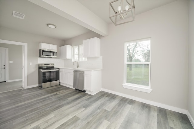 kitchen featuring plenty of natural light, appliances with stainless steel finishes, and white cabinets