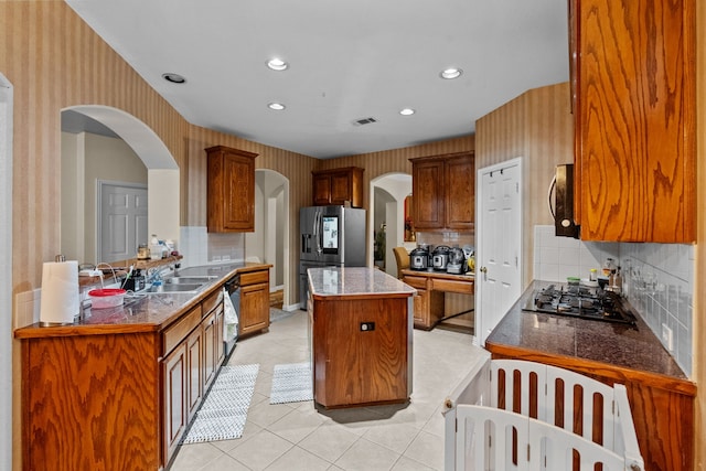 kitchen featuring stainless steel appliances, a kitchen island, sink, and backsplash