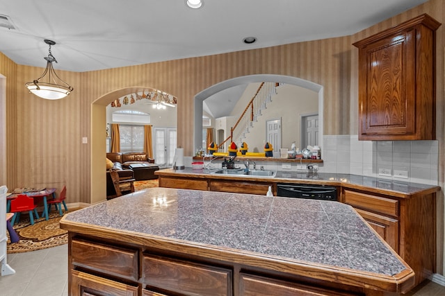 kitchen with sink, light tile patterned floors, a center island, black dishwasher, and tasteful backsplash