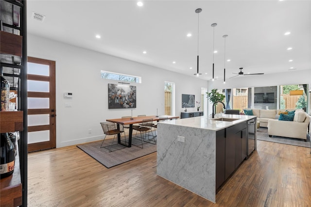 kitchen featuring a spacious island, decorative light fixtures, sink, and hardwood / wood-style flooring