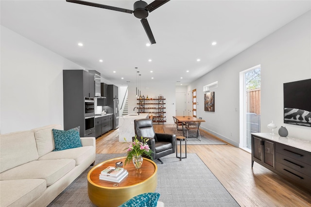 living room with sink, ceiling fan, and light wood-type flooring