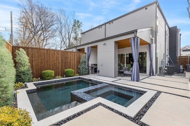 rear view of property featuring a patio area and a pool with hot tub