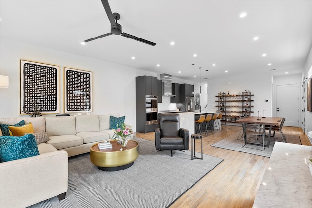 living room featuring ceiling fan, sink, and light hardwood / wood-style flooring