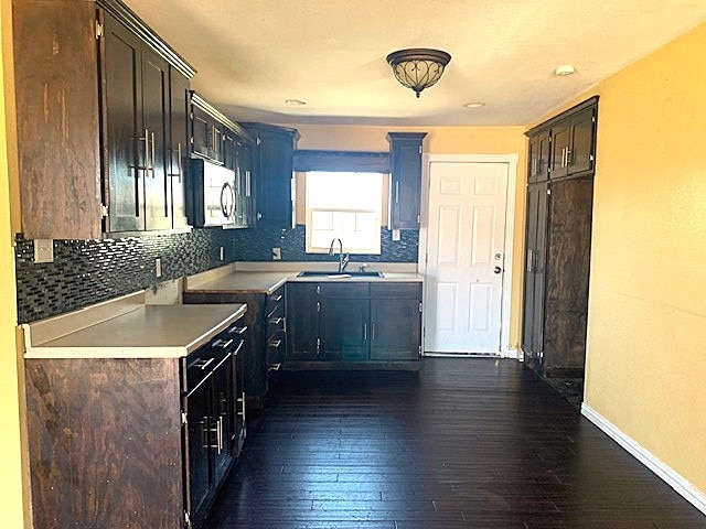 kitchen featuring dark brown cabinetry, sink, and dark hardwood / wood-style floors