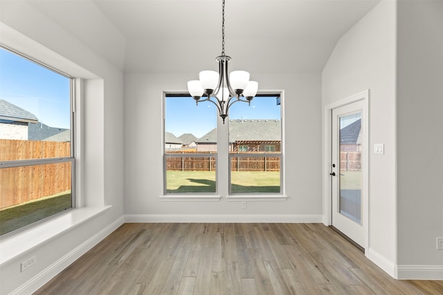 unfurnished dining area with an inviting chandelier and light wood-type flooring