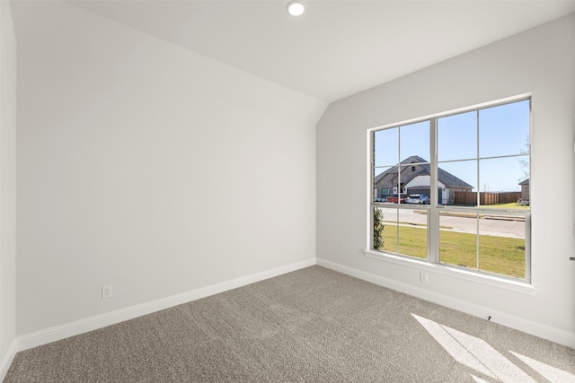 carpeted empty room featuring vaulted ceiling