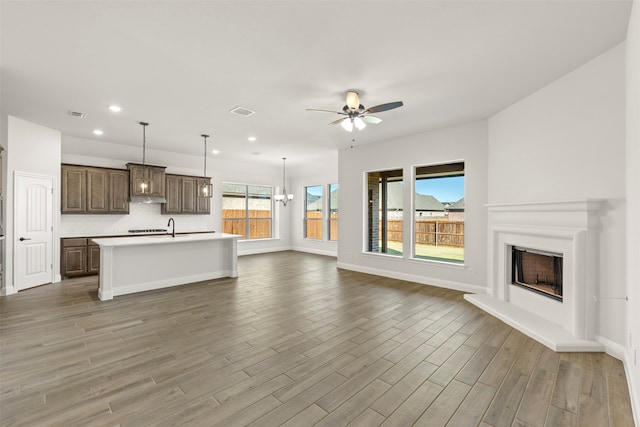 unfurnished living room featuring ceiling fan with notable chandelier, sink, and hardwood / wood-style floors