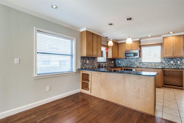 kitchen featuring pendant lighting, crown molding, kitchen peninsula, and hardwood / wood-style flooring