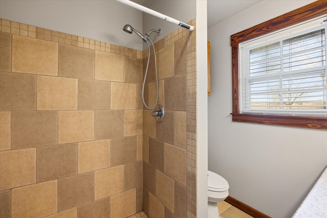 bathroom featuring tiled shower, tile patterned floors, and toilet