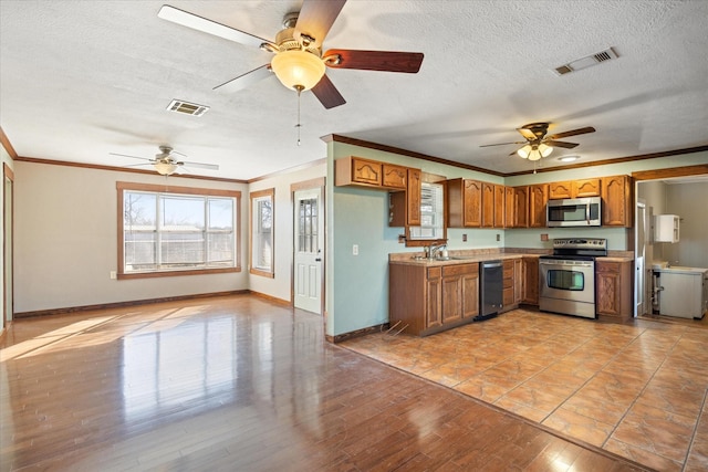 kitchen with sink, light hardwood / wood-style flooring, appliances with stainless steel finishes, ornamental molding, and a textured ceiling