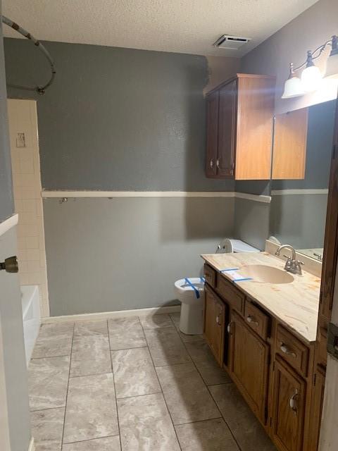 full bathroom featuring shower / tub combination, tile patterned flooring, vanity, a textured ceiling, and toilet