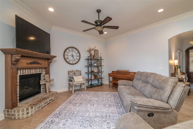 living room featuring tile patterned flooring, ornamental molding, a brick fireplace, and ceiling fan