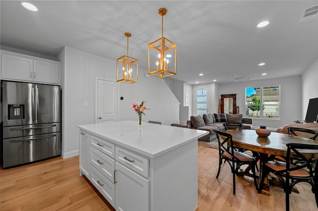 kitchen with white cabinetry, decorative light fixtures, stainless steel fridge with ice dispenser, a kitchen island, and light hardwood / wood-style floors