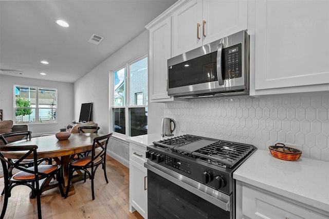 kitchen featuring tasteful backsplash, range with gas cooktop, light hardwood / wood-style floors, and white cabinets