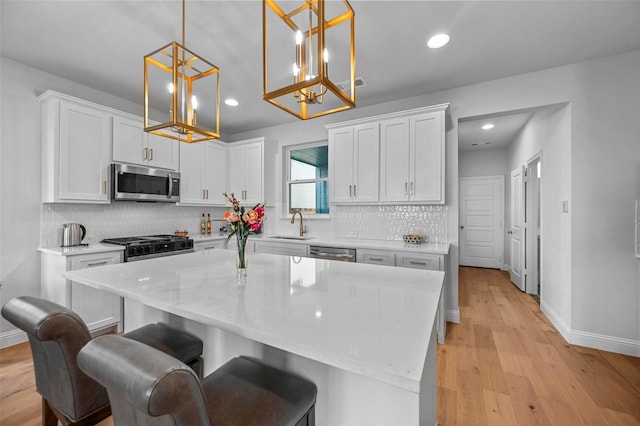 kitchen with white cabinetry, stainless steel appliances, a center island, and hanging light fixtures