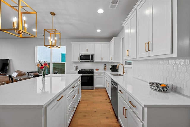 kitchen with sink, a center island, hanging light fixtures, appliances with stainless steel finishes, and white cabinets