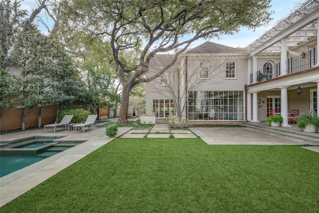 rear view of house featuring an in ground hot tub, a balcony, a patio area, and a lawn