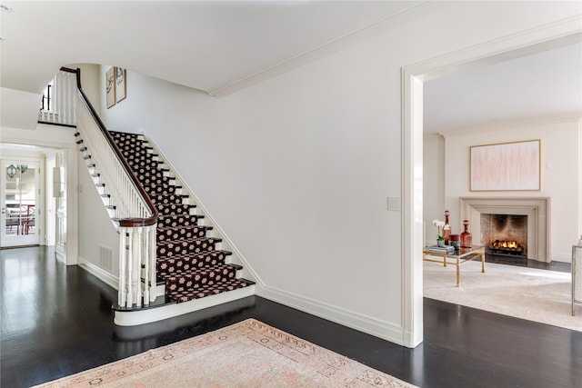 stairs with crown molding and wood-type flooring