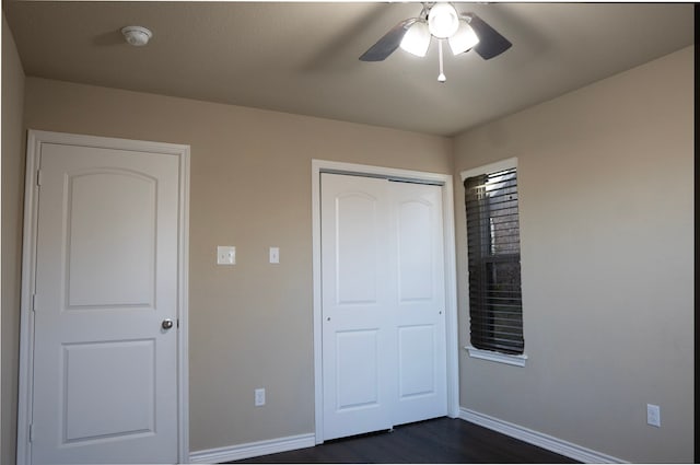 unfurnished bedroom with dark wood-type flooring, ceiling fan, and a closet