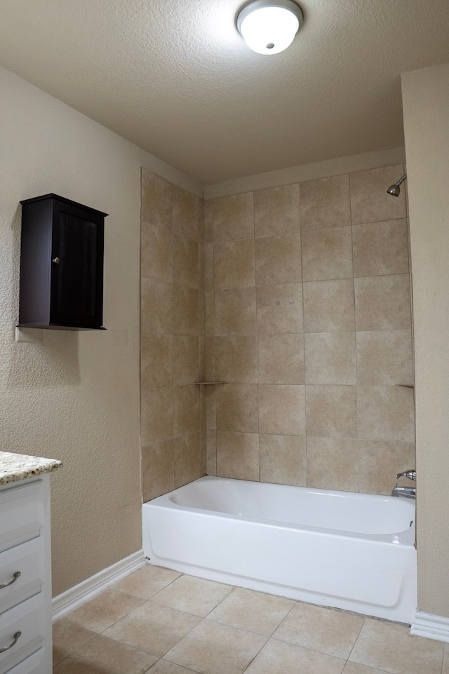 bathroom featuring tile patterned flooring, vanity, a textured ceiling, and tiled shower / bath