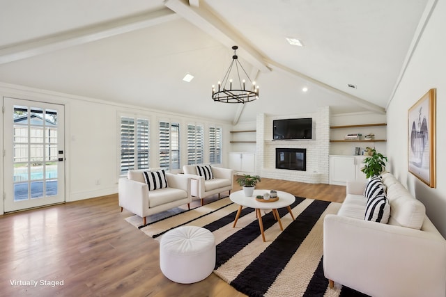 living room featuring hardwood / wood-style flooring, vaulted ceiling with beams, a notable chandelier, and a fireplace