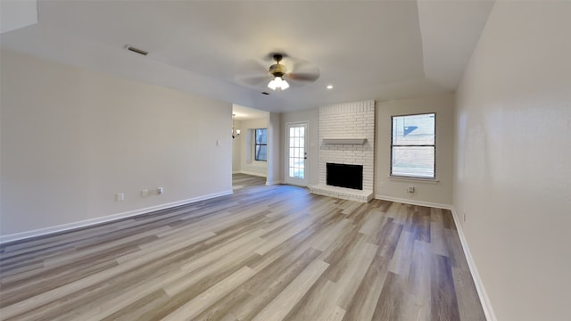 unfurnished living room featuring a fireplace, ceiling fan, and light wood-type flooring